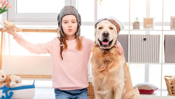 Menina jogar no piloto de avião com cão golden retriever — Fotografia de Stock