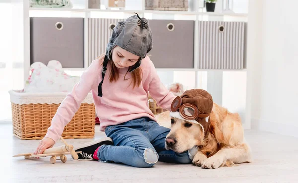 Meisje spelen in vliegtuig piloot met golden retriever hond — Stockfoto