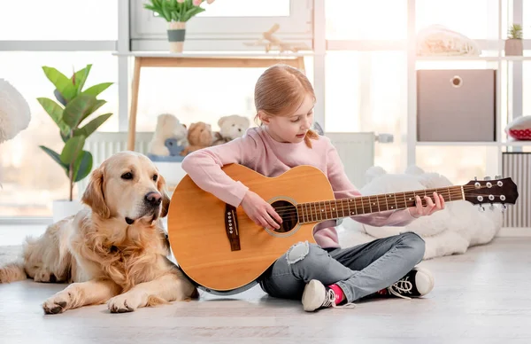 Liten flicka med gitarr och golden retriever hund — Stockfoto