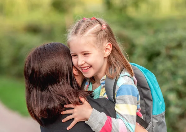 School meisje knuffelen moeder na lessen — Stockfoto