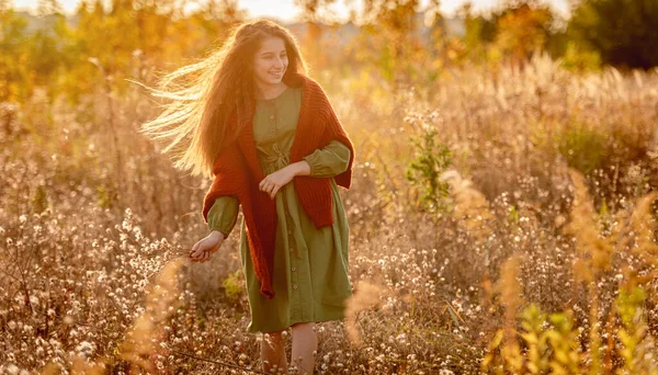 Jeune fille avec des fleurs d'automne sur le terrain — Photo