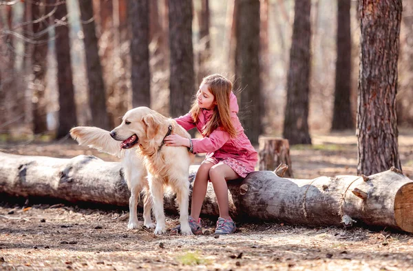 Bambina con cane golden retriever nel bosco — Foto Stock