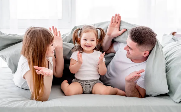 Família debaixo do cobertor na cama — Fotografia de Stock