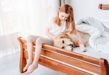 Yatağında golden retriever köpeği olan kız