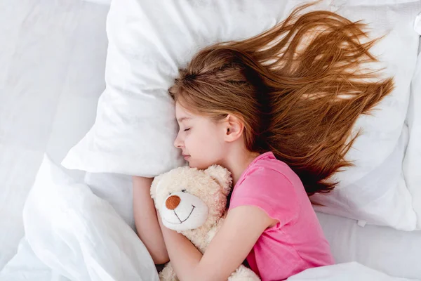 Menina na cama com ursinho de pelúcia — Fotografia de Stock