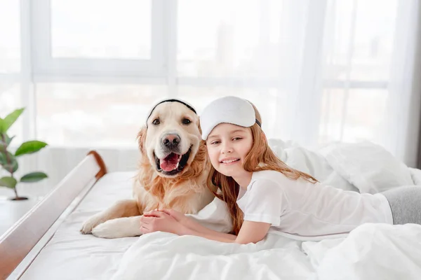 침대에 황금 리트리버 개를 데리고 있는 소녀 — 스톡 사진
