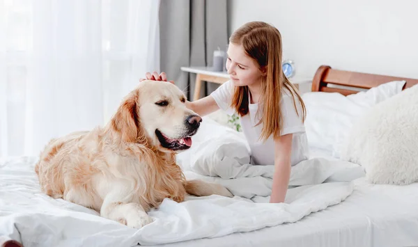 Ragazza con cane golden retriever nel letto — Foto Stock