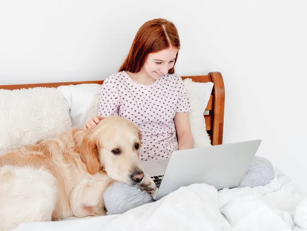 Girl with laptop and golden retriever dog