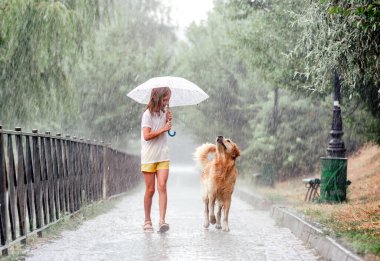 Yağmurlu günlerde Golden Retriever köpeği olan kız