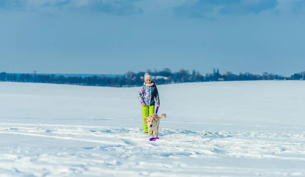 Meisje hardlopen met hond in de sneeuw — Stockfoto