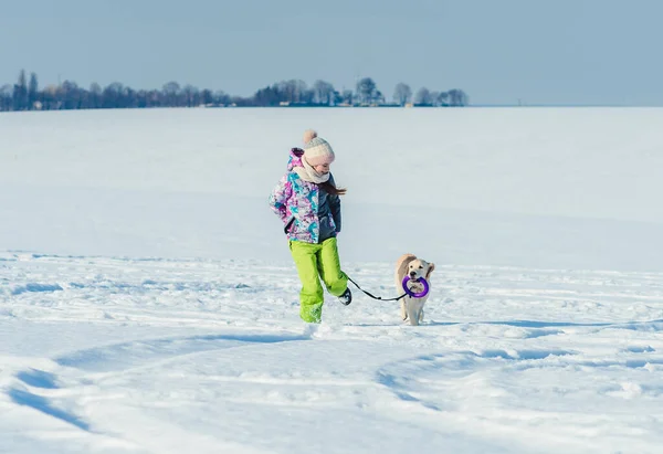 Flicka som springer med hund i snö — Stockfoto