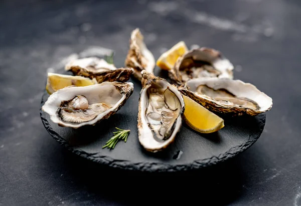 Oysters with lemon on platter — Stock Photo, Image