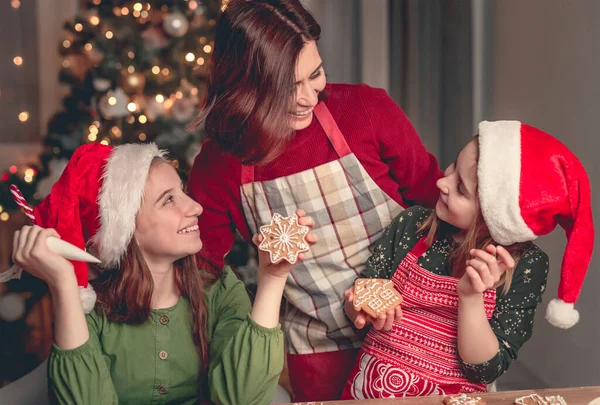 Mãe sorridente com filhas assando pão de gengibre — Fotografia de Stock