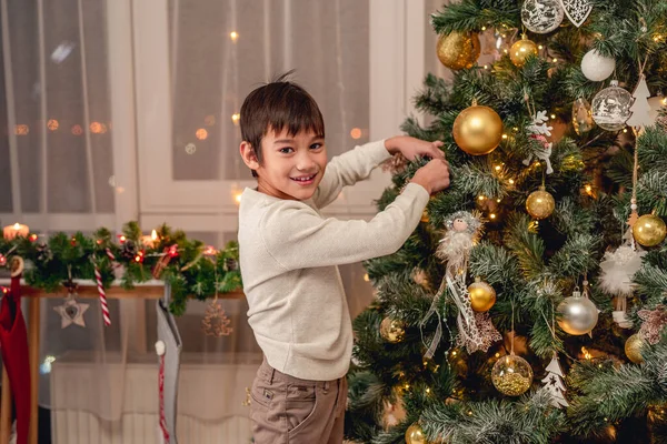 Muchacho sonriente colgando bola en el árbol de Navidad — Foto de Stock