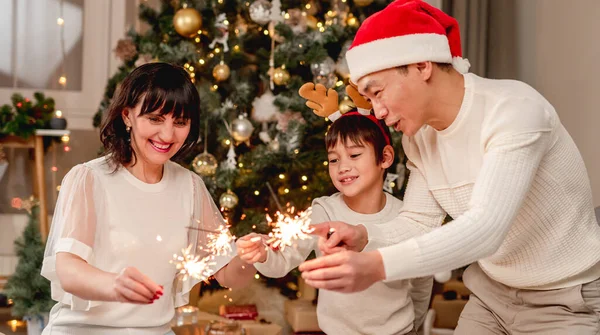 Familia feliz con bengalas bajo el árbol de Navidad —  Fotos de Stock