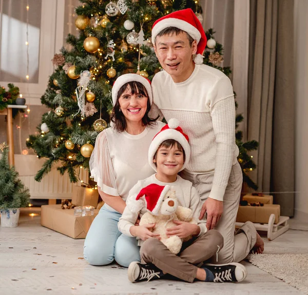 Feliz familia sentada bajo el árbol de Navidad —  Fotos de Stock