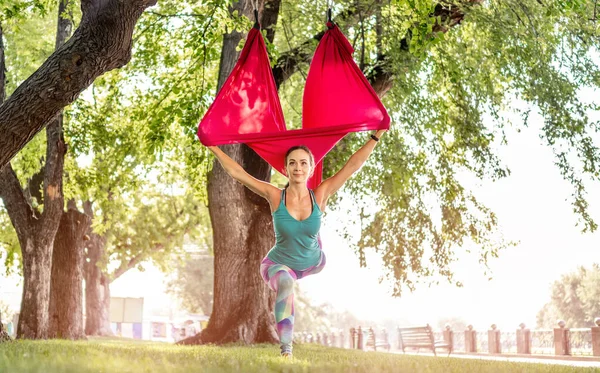 体育女孩在大自然的吊床上练习飞行瑜伽 用一条腿伸展自己的身体 夏季体操户外运动中的活跃女性 — 图库照片