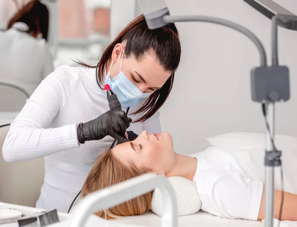 Meister macht Augenbrauen dauerhaft schminken — Stockfoto