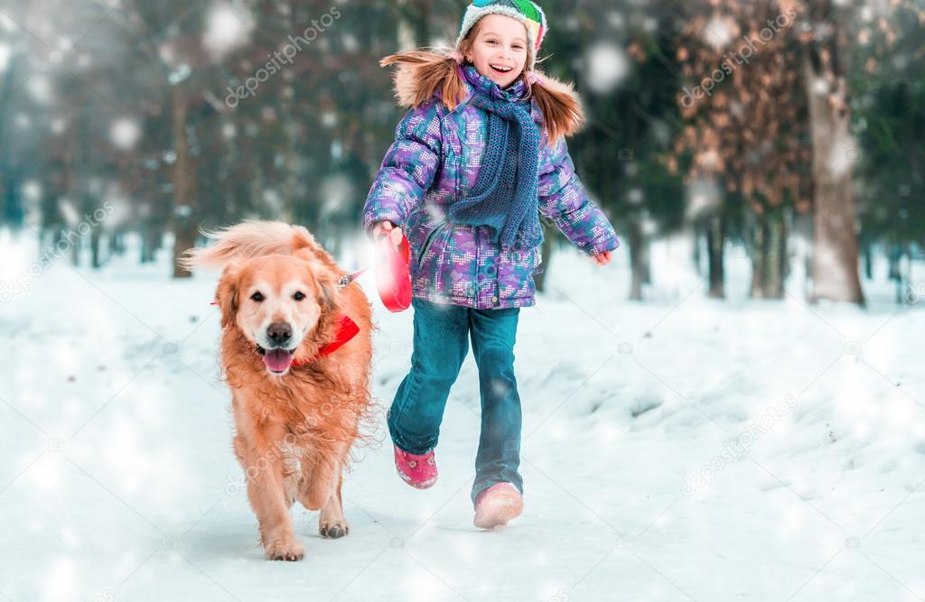 Little girl with dog on the snow in winter
