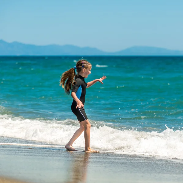 Meisje in een wetsuit op het strand — Stockfoto