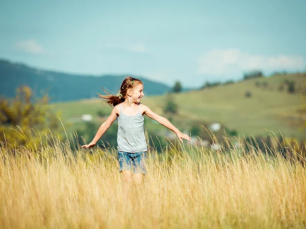 Dziewczynka biegnie przez łąkę — Zdjęcie stockowe