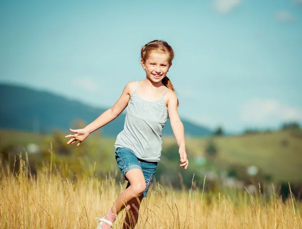 Liten flicka går genom en äng — Stockfoto