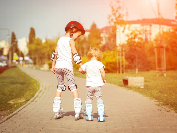 Zwei kleine Schwestern auf Rollschuhen — Stockfoto