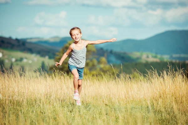 Kleines Mädchen läuft durch eine Wiese — Stockfoto