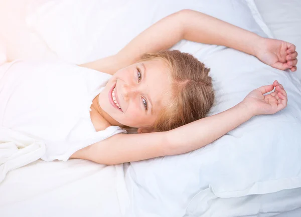 Niña de seis años en una cama blanca — Foto de Stock