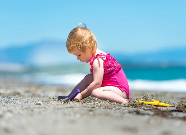 Маленькая симпатичная девочка, играющая в песке — стоковое фото