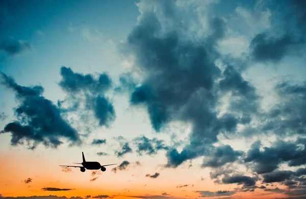 Vliegtuig in hemel bij zonsondergang — Stockfoto