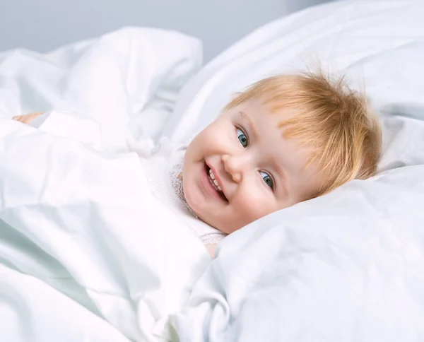 Bebê deitado em uma cama branca — Fotografia de Stock