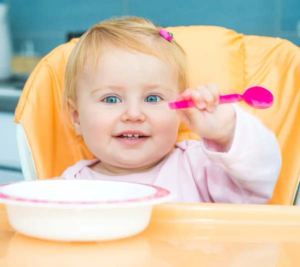 Jeden rok stará dívka v židličku na krmení — Stock fotografie