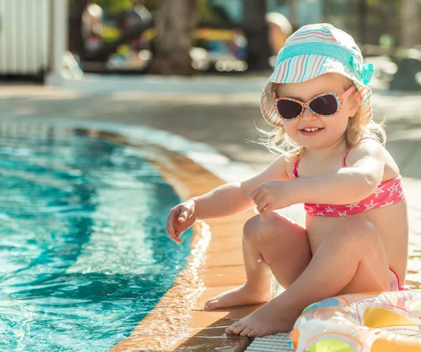 小さな女の子が、プールのそばに座って — ストック写真