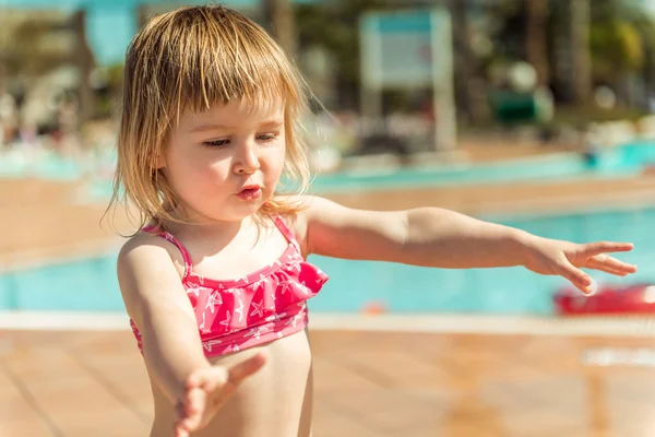 Kleines Mädchen sitzt in der Nähe des Pools — Stockfoto