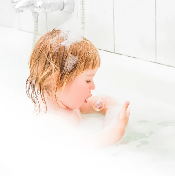 Cute two year old baby bathes in a bath with foam — Stock Photo, Image