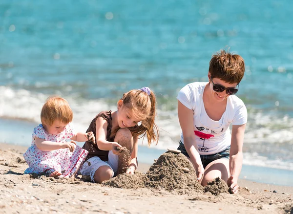 Mãe e filhas brincando na areia — Fotografia de Stock