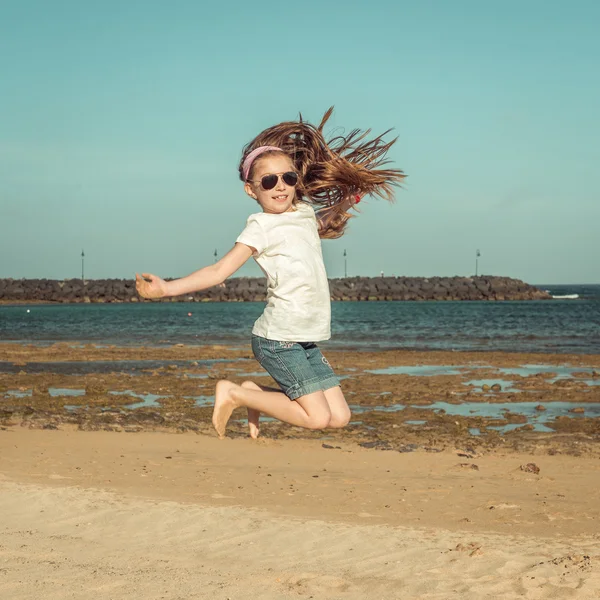 Liten flicka hoppa på stranden — Stockfoto