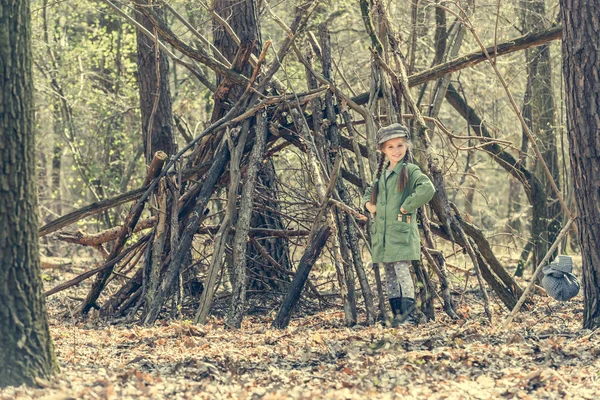 Little  girl builds  hut in  woods — Stock Photo, Image