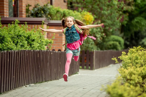 Маленькая девочка бежит из школы — стоковое фото