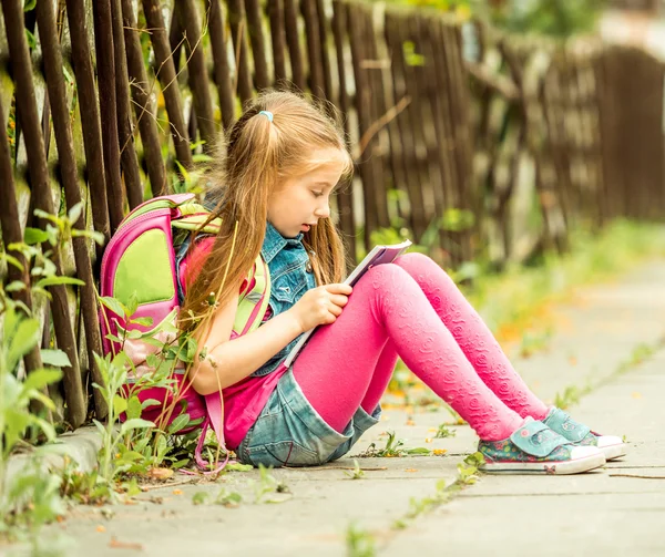 Schoolmeisje leesboek op straat — Stockfoto