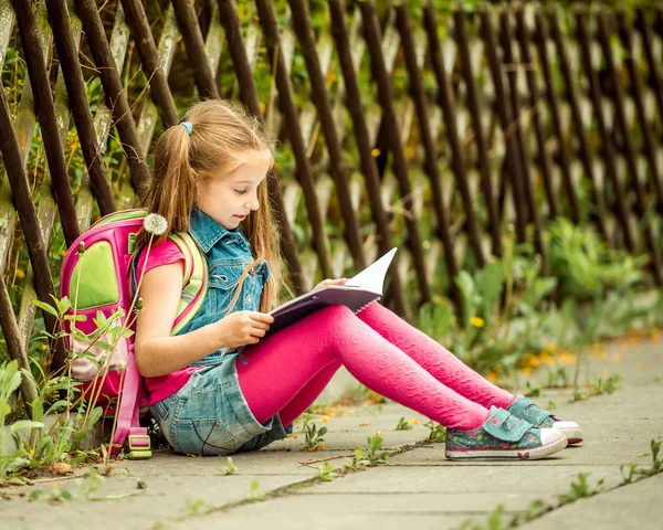 Schoolmeisje lezen boek op de straat — Stockfoto