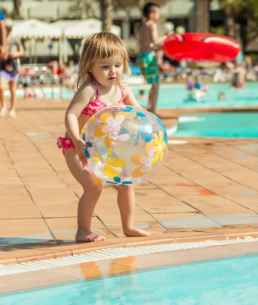 小さな女の子が、プールのそばに座って — ストック写真