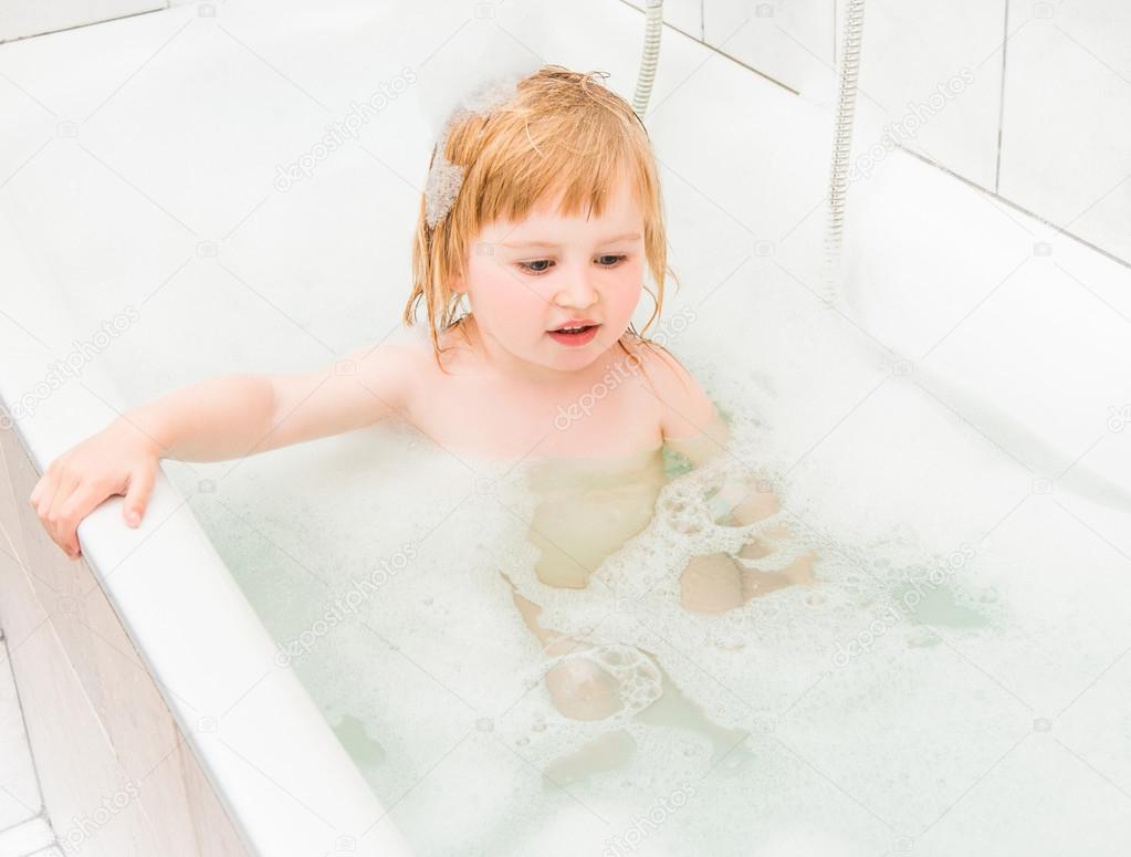 cute two year old baby bathes in a bath with foam 