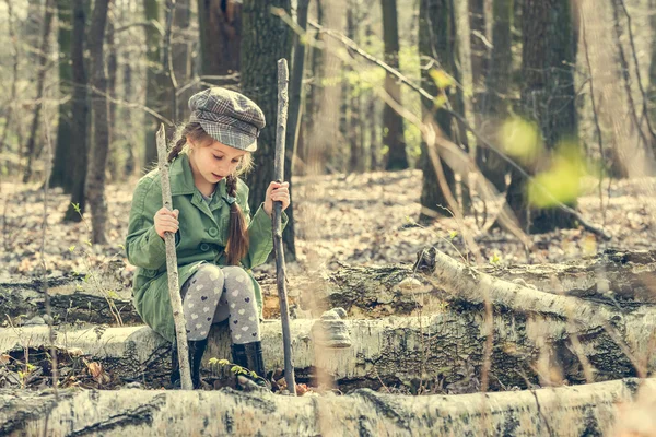 Liten flicka i skogen sitter på stubben — Stockfoto