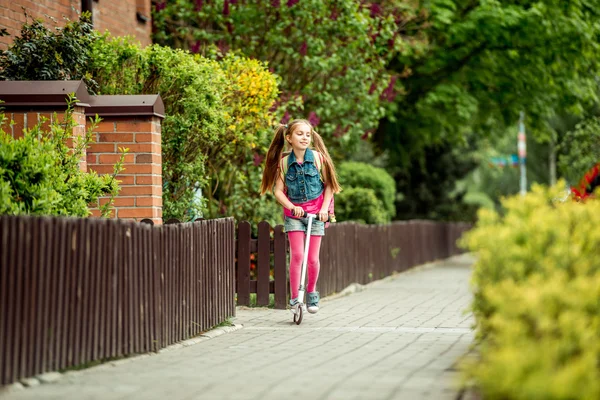 Girl goes to school on a scooter — Stock Photo, Image