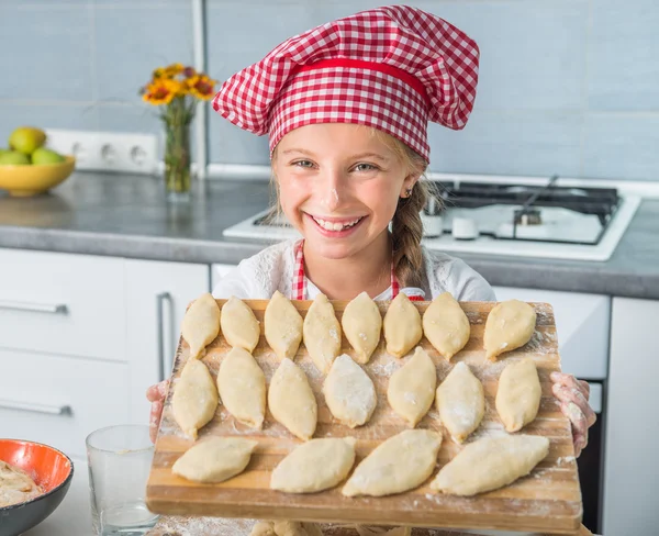 Little girl with raw patties on board — Stock Photo, Image