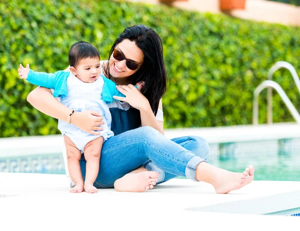 Madre joven con su bebé cerca de la piscina — Foto de Stock