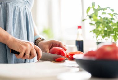 Women's Hands Slicing Tomato At Home In The Kitchen