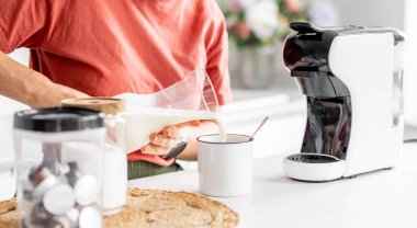 Evde kahveye süt ekleyen kadın, yakın plan.